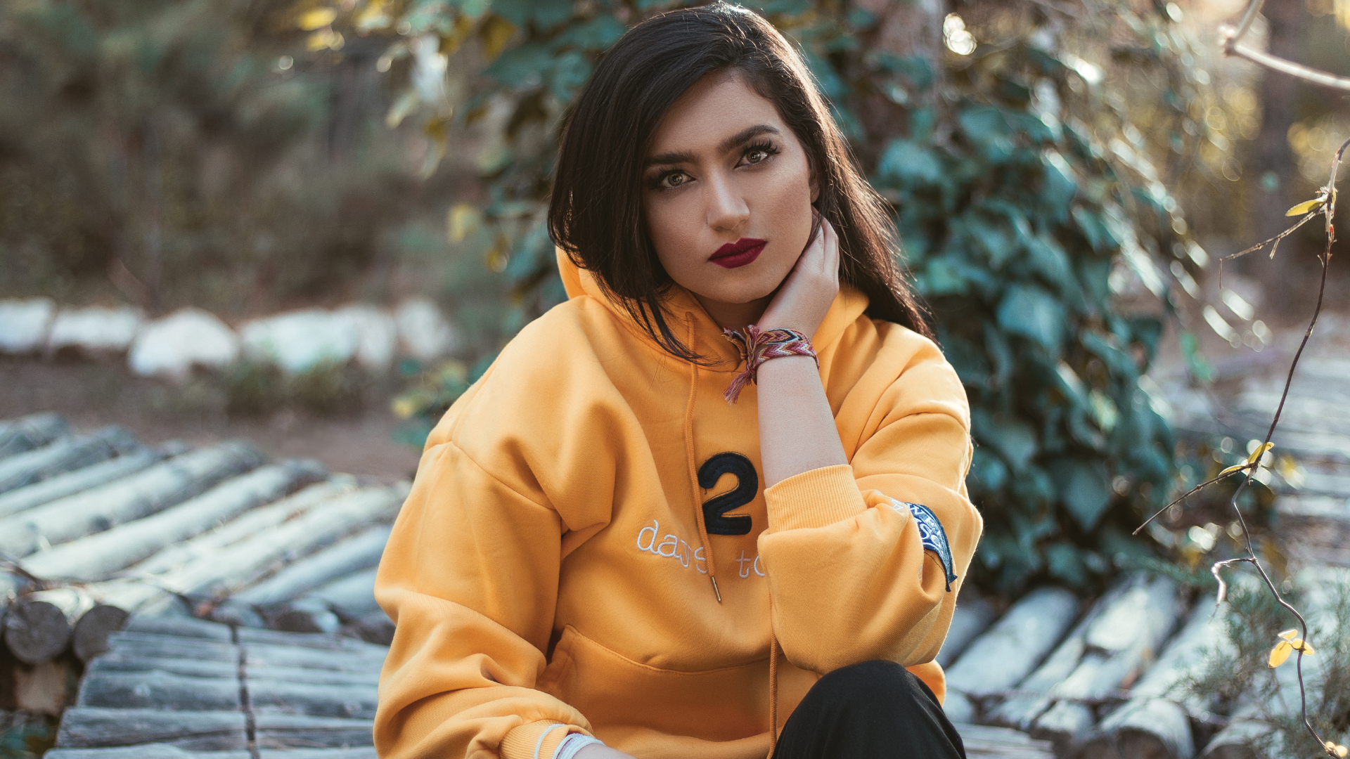 a woman staring at the camera wearing an orange custom embroidered hoodie with a number and some letters on it