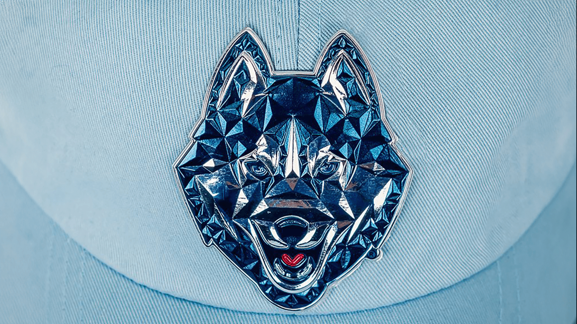 A unique beveled patch depicting a geometric, faceted wolf’s head in metallic blue tones on a light blue cap, creating a reflective, jewel-like appearance