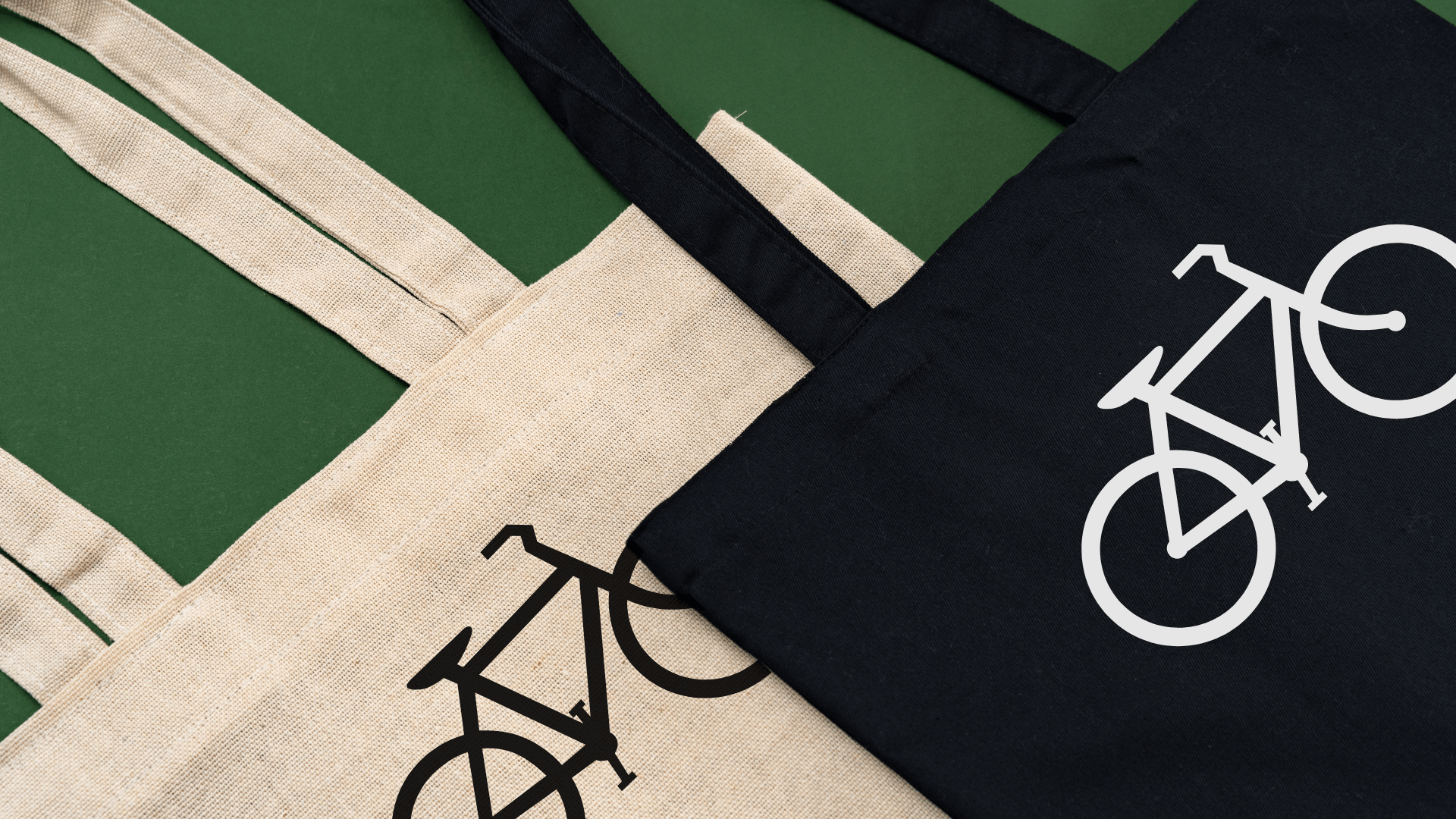 two custom canvas tote bags, one tan and one black both with bicycle logos