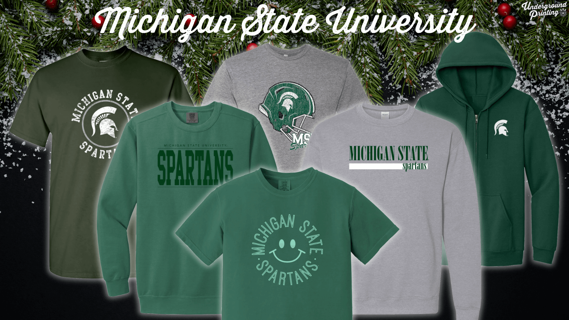 Michigan State University apparel display with a festive holiday background, showcasing various shirts, hoodies, and sweatshirts in green and gray with "Michigan State Spartans" and Spartan helmet logos.