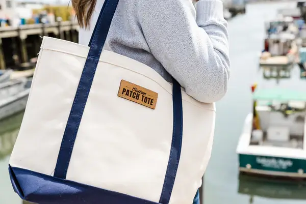 A woman warrying a custom patch tote bag that says patch tote