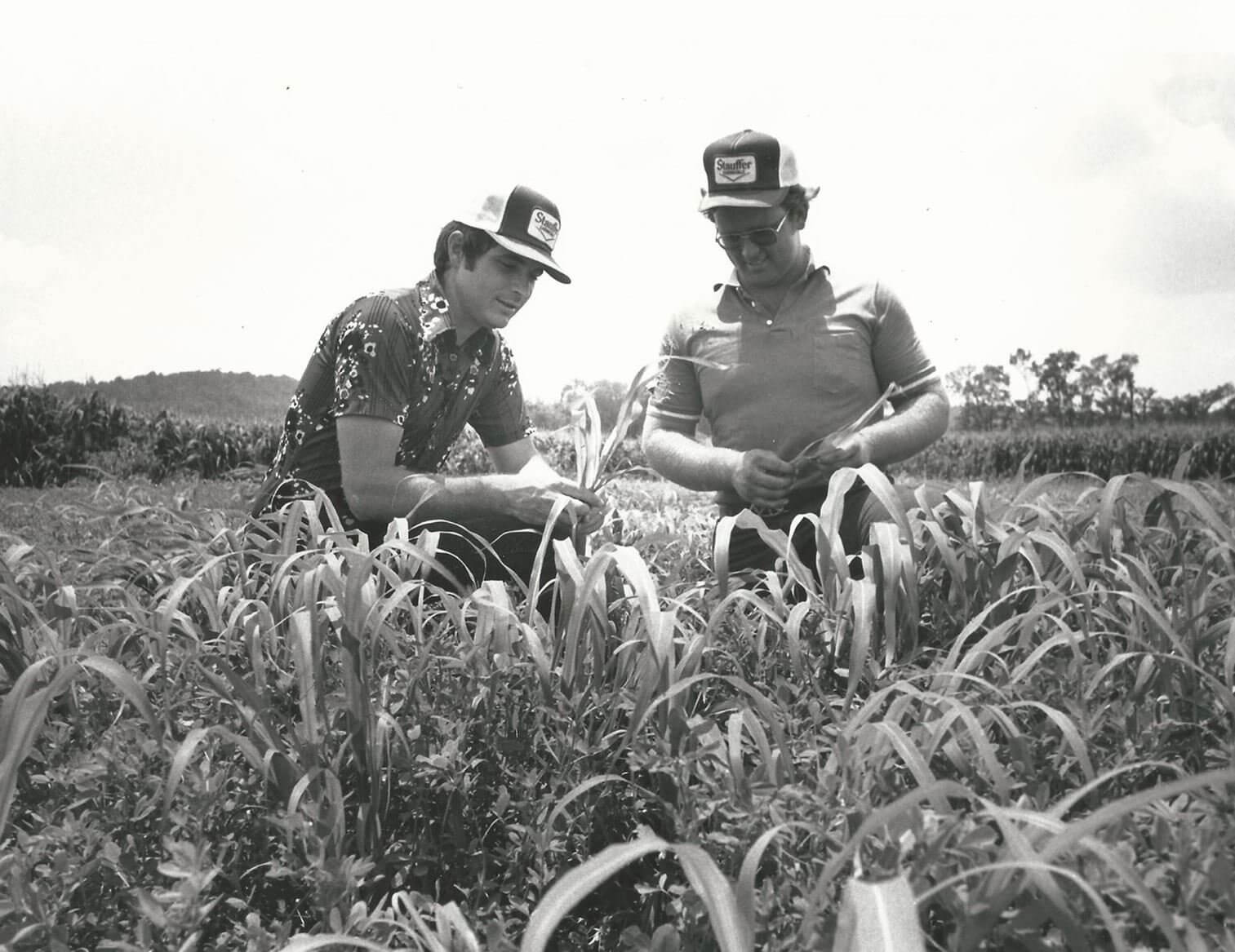 two farmers wearing custom trucker hats in a field