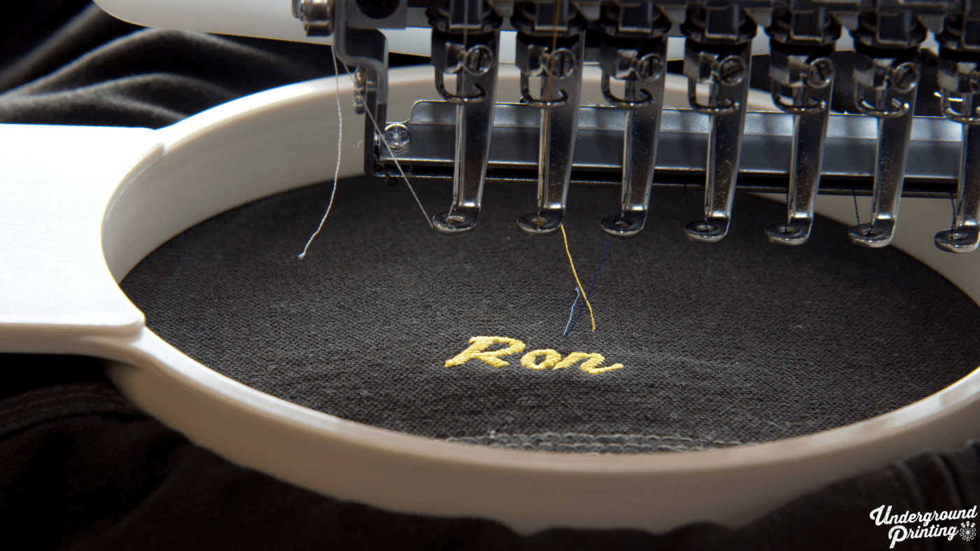 an embroidery machine stitching text onto a black hoodie