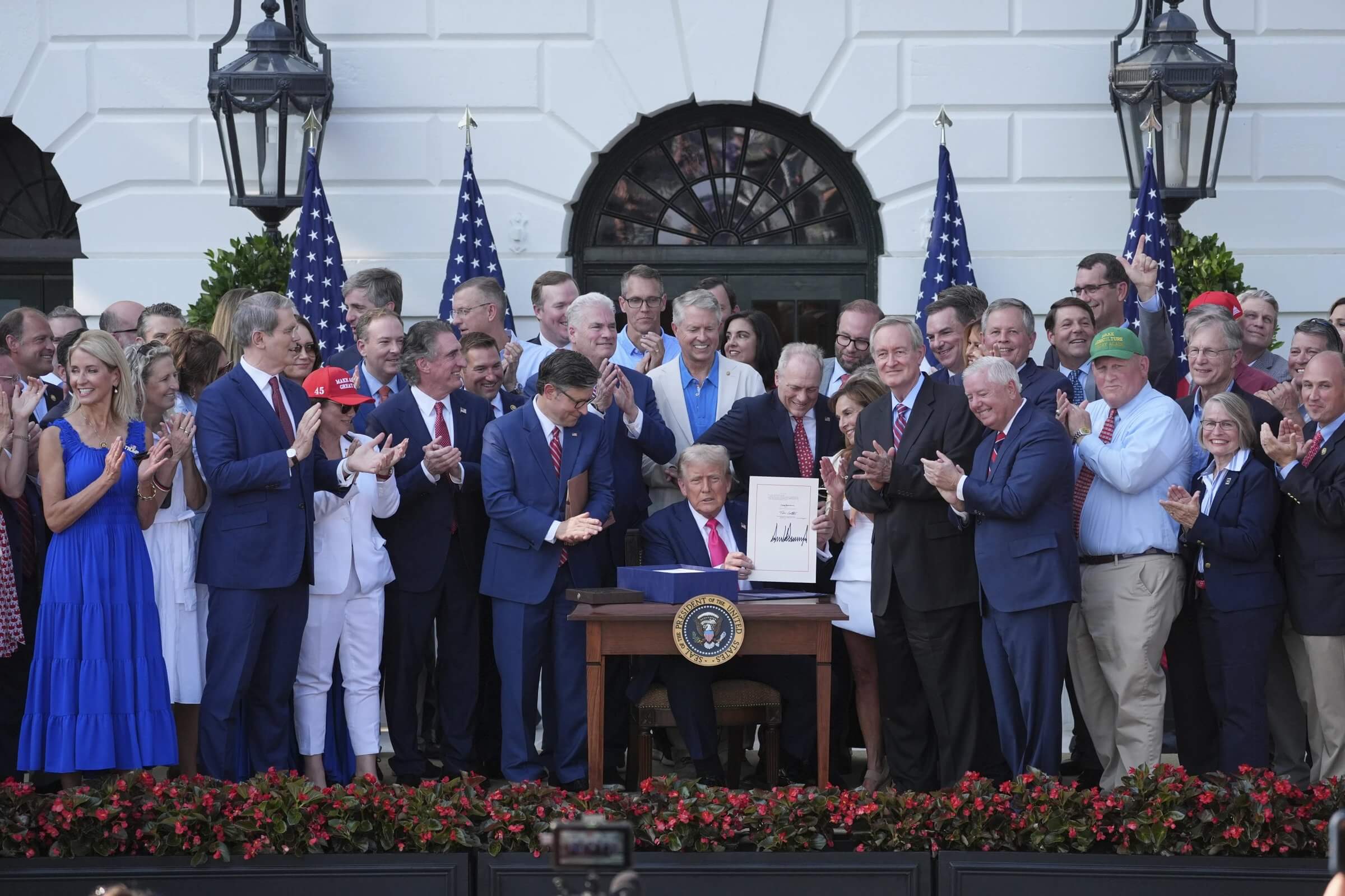 President Donald Trump signs his signature bill of tax breaks and spending cuts at the White House, Friday, July 4, 2025, in Washington, surrounded by members of Congress. (AP Photo/Evan Vucci)