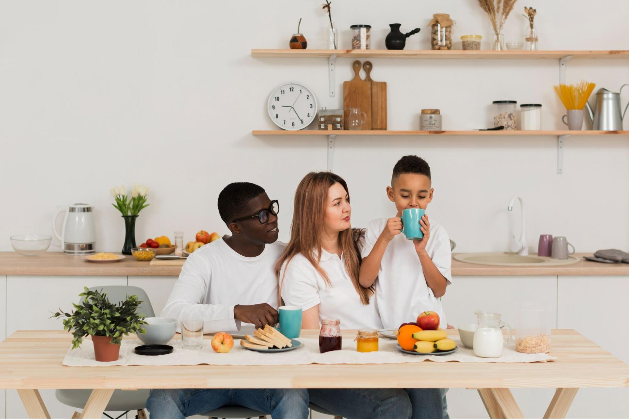 happy family with kid drinking from mom’s coffee mug in kitchen