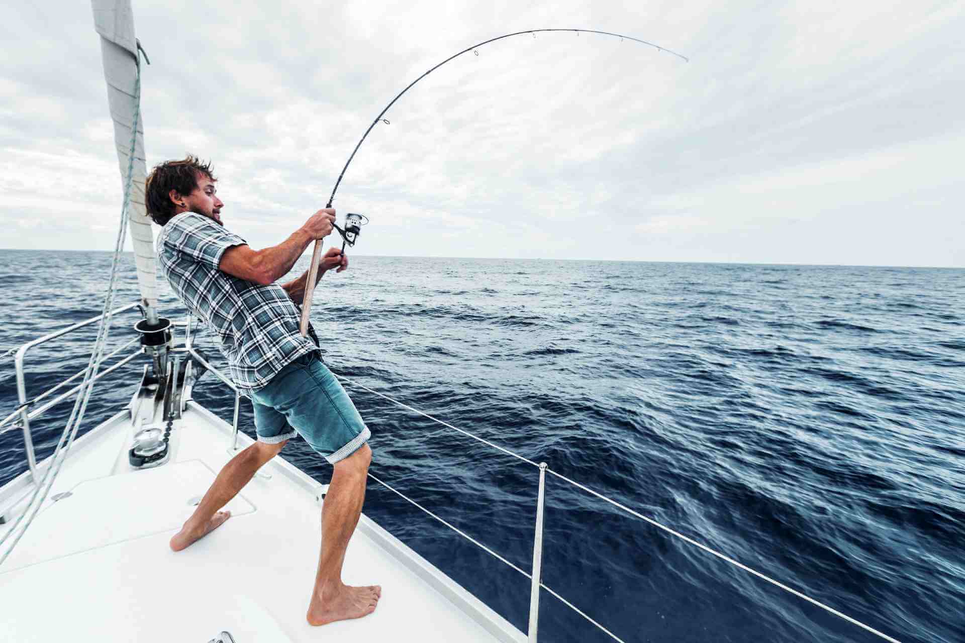 Angler on a boat holding a bent fishing rod, showcasing the thrill of catching a fish.
