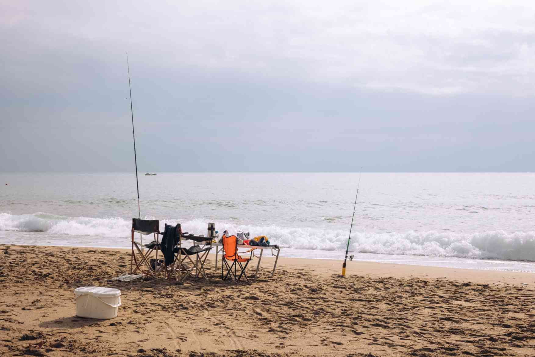 Two chairs with fishing rods by the beach