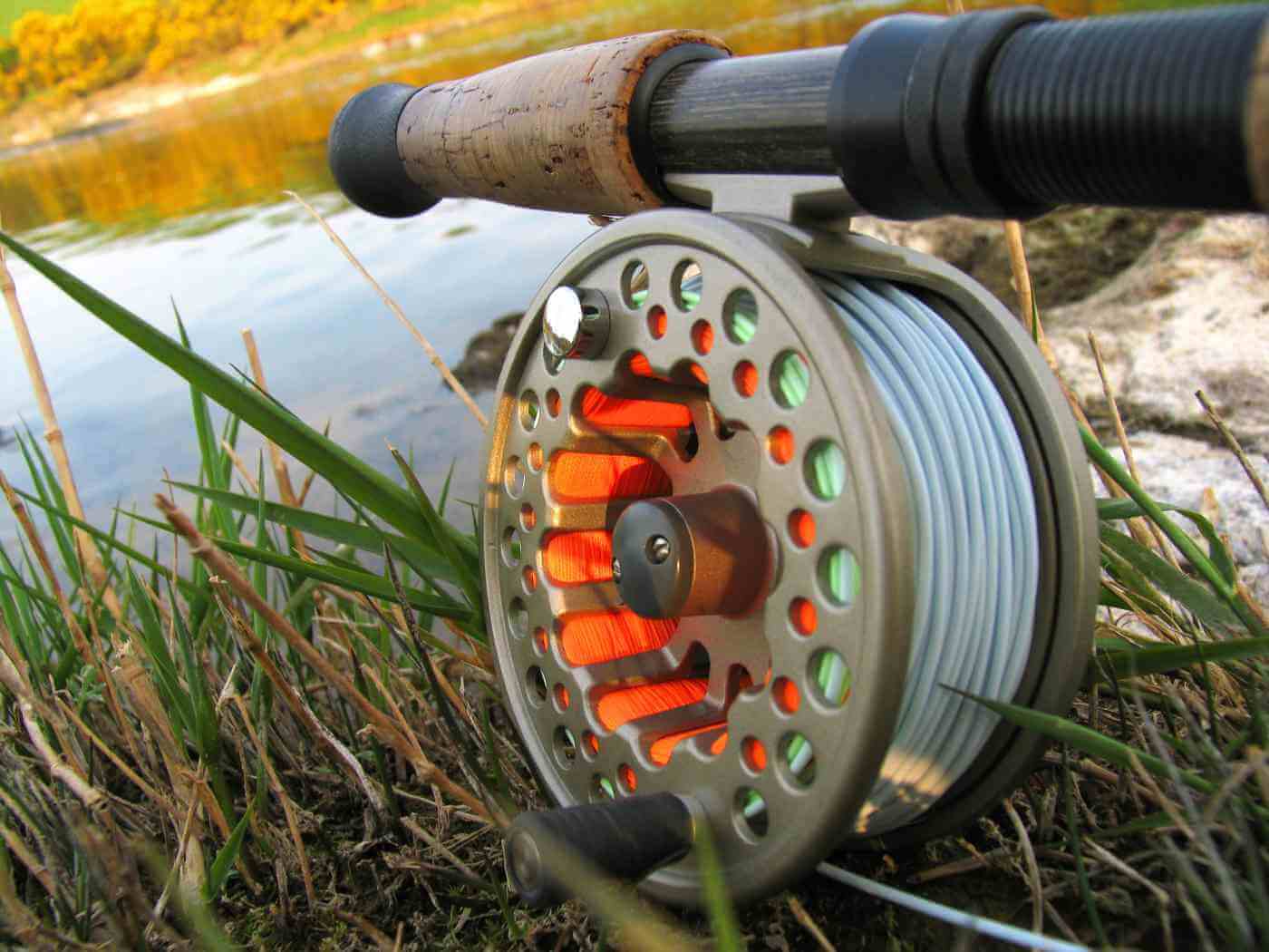 Close-up of a fly fishing reel with line near the water’s edge