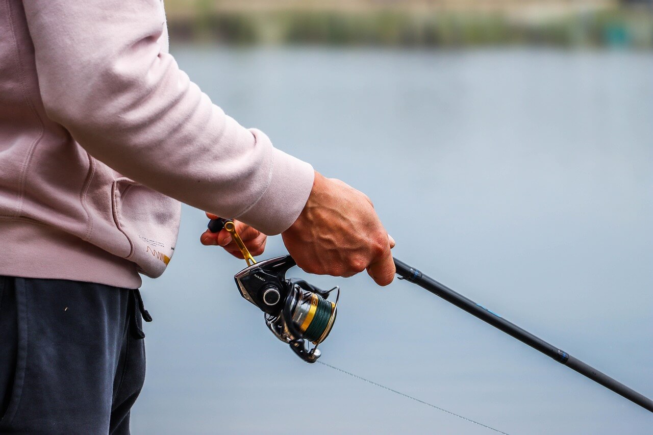 Fisherman holding a rod and reel while managing drag settings