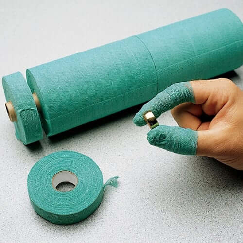 Image of rolls of green tape and a hand with two fingers wrapped holding a gold ring.