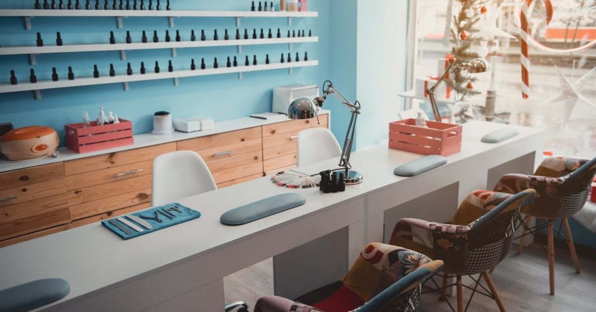 Manicure tools rest on a salon desk as cozy chairs line up for clients in a clean, modern workspace.