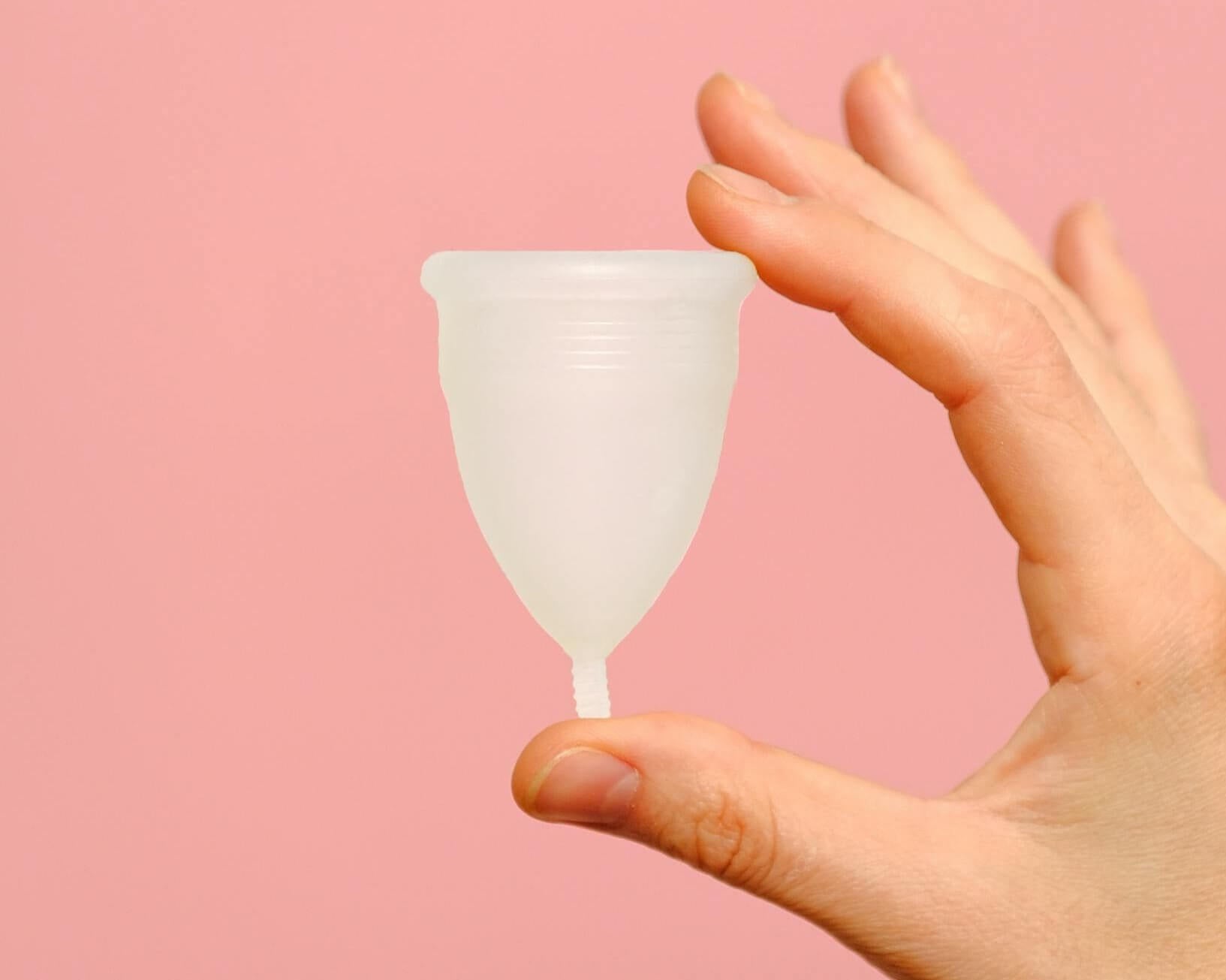 a white diva cup against a pink backround