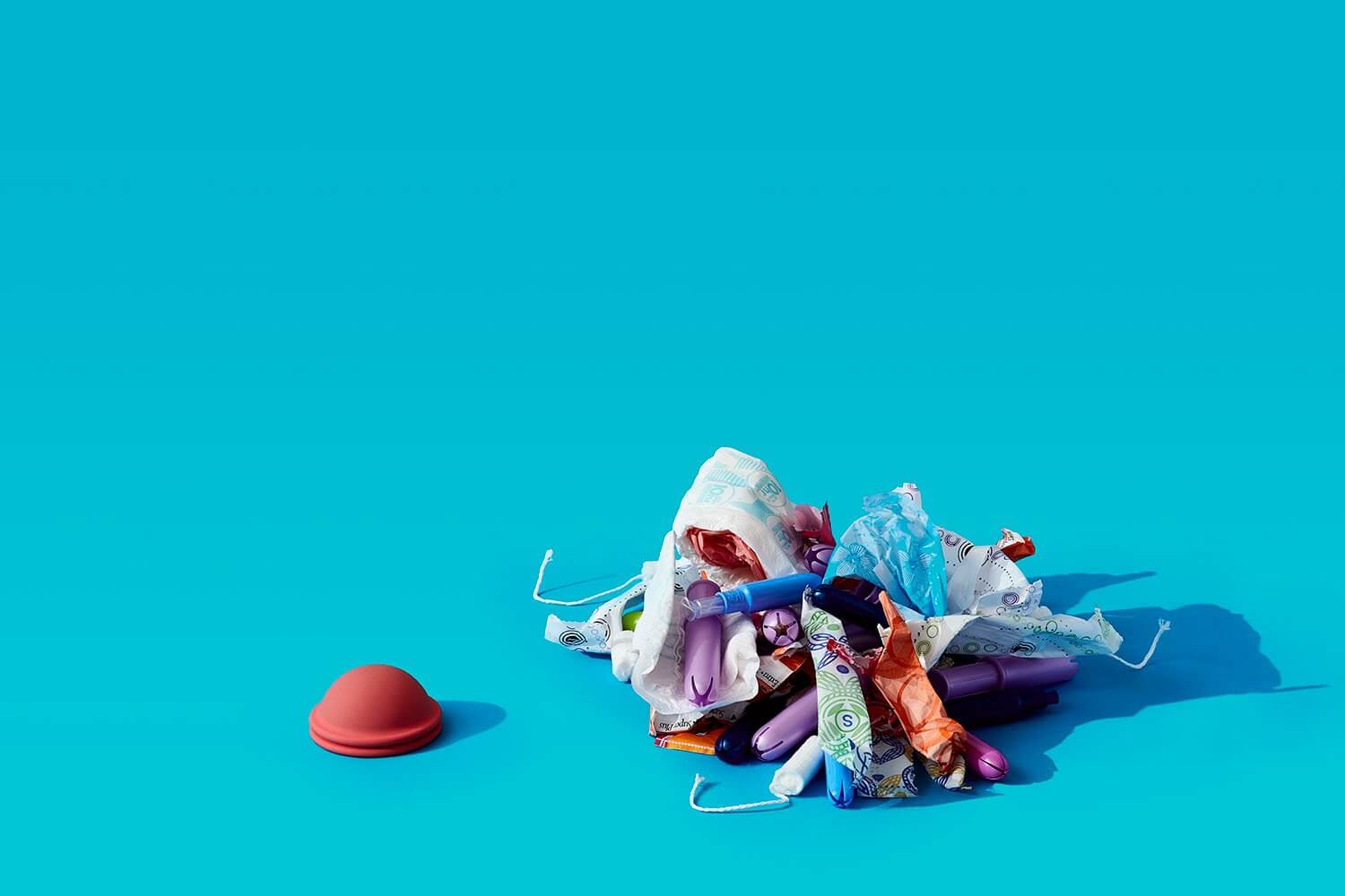 a menstrual disc next to a pile of disposable tampons