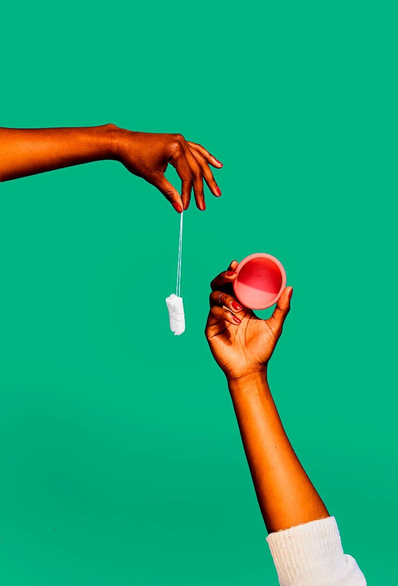 a tampon and a pink menstrual disc against a green background