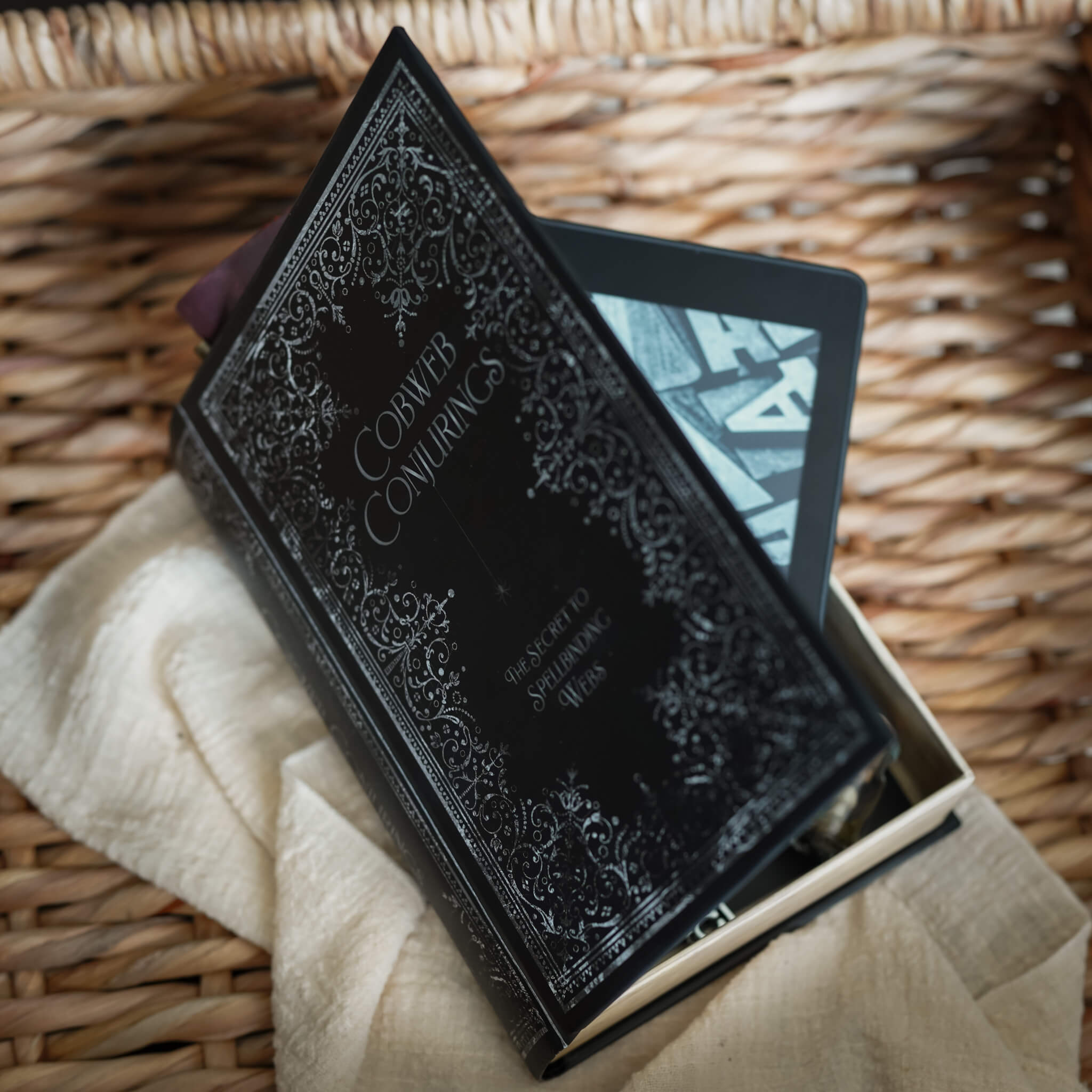 LitJoy's Cobwebs and Conjurings Secret Book with black cover and white filigree and text