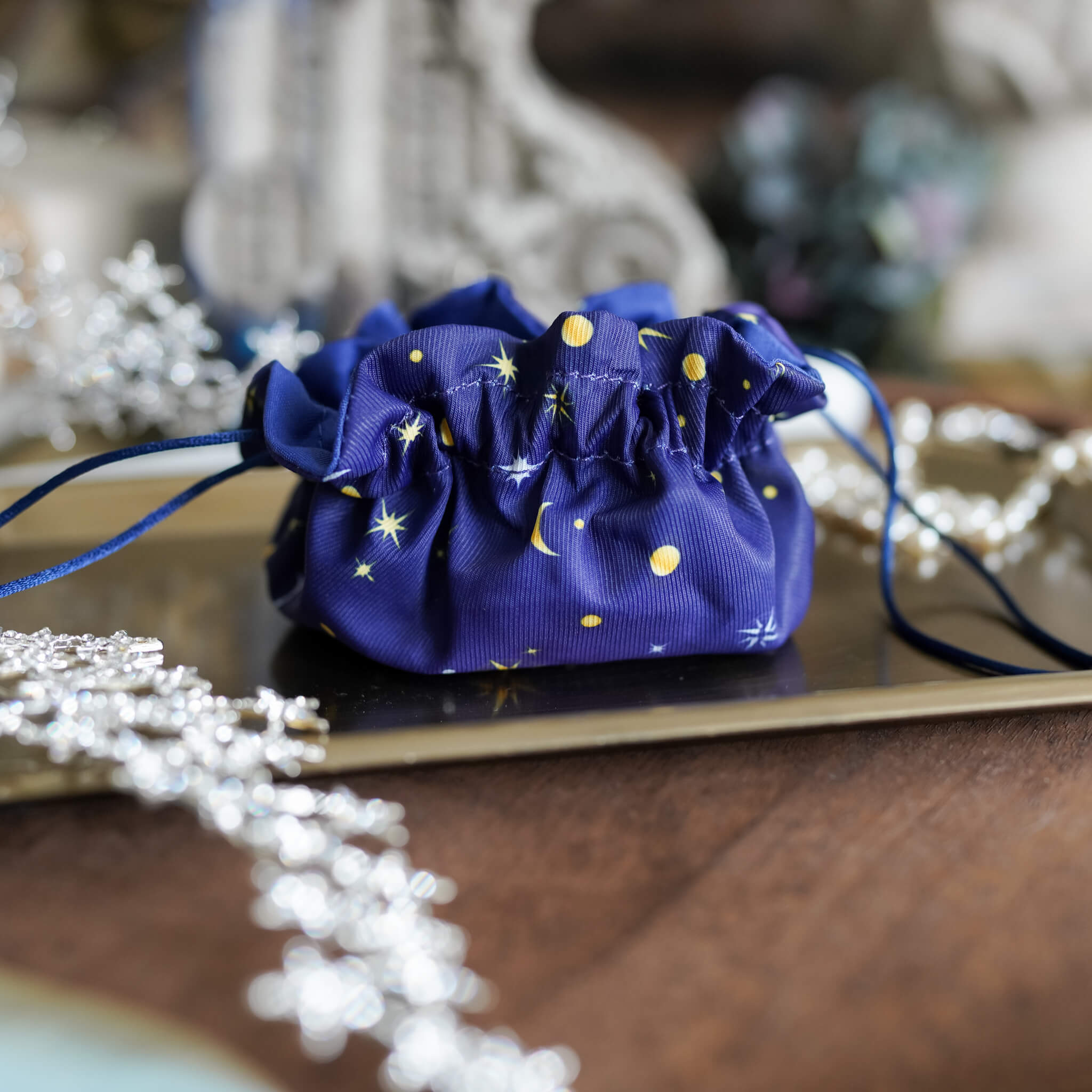 The Stardust Thief blue drawstring bag with yellow stars and moons