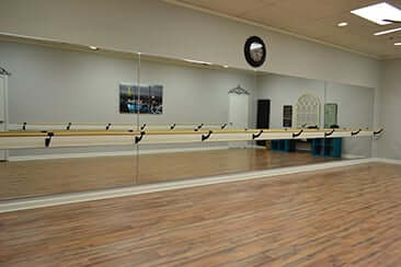 At home barre dance studio featuring adjustable wall-mounted ballet barres and hardwood floors with mirrors