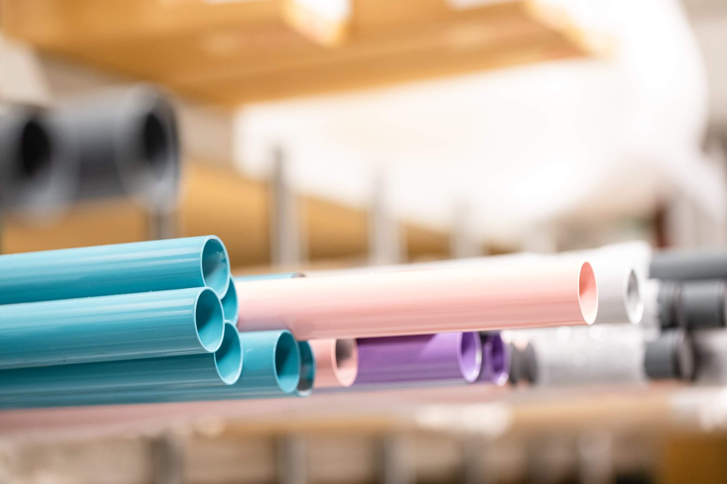 Close-up view of colorful metal tubes used to craft professional ballet barres, showcasing pastel shades of teal, pink, purple, and silver in a workshop setting.