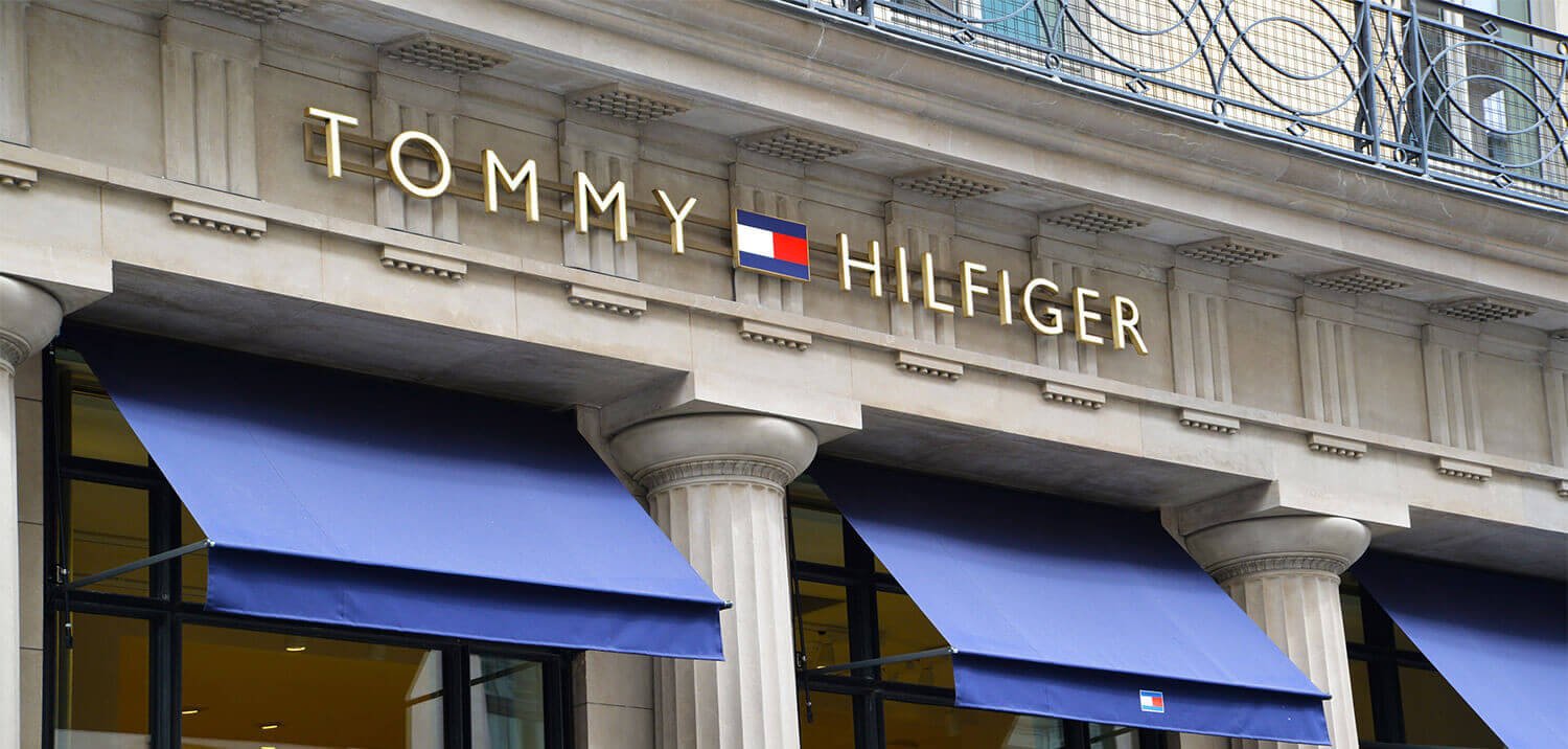 A logo sign outside of a Tommy Hilfiger retail store location in