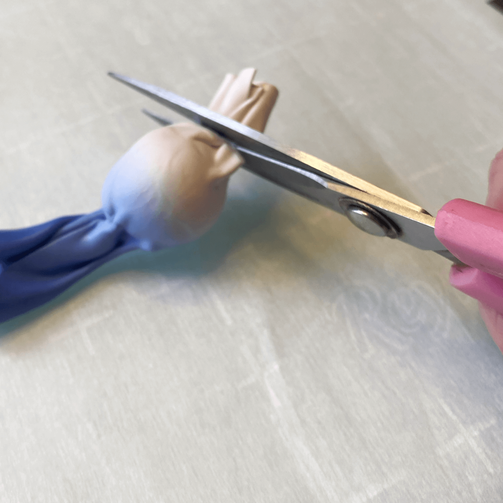 Using scissors to remove the excess clay from the skinner blend wrapped around the base bead.
