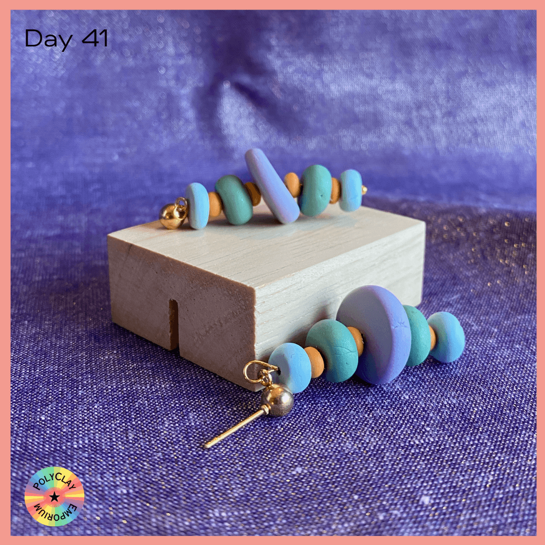 Blue toned polymer clay cairn earring with orange separaters