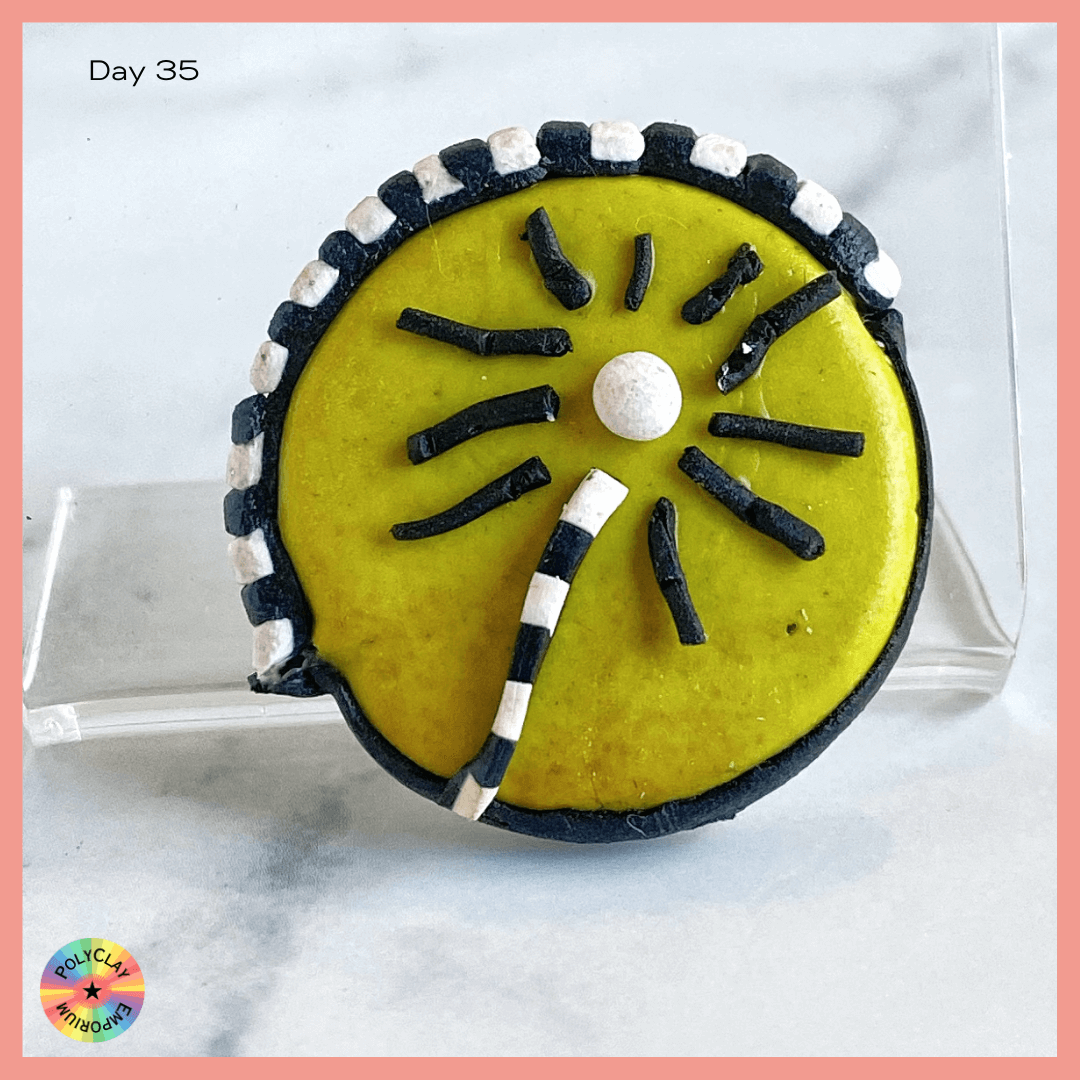 Polymer Clay bead:  Citron wafer fully edged with black, half-edged with black and white stripes.  Center is a flower with black and white striped stem, black petals and a white center.