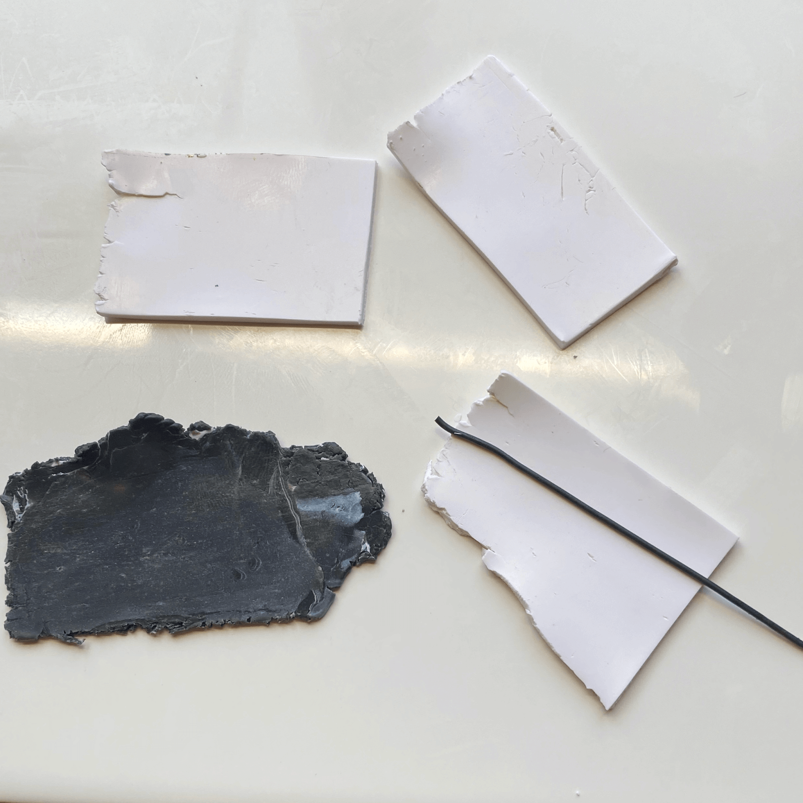 Slabs of white and black polymer clay laid out with a thin black string.