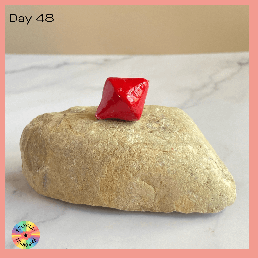 A scarlet polymer clay bicone bead.