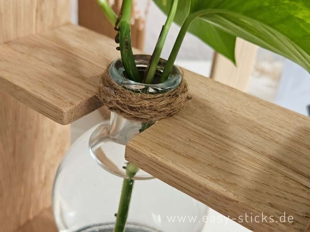 Glasflasche wird mit Jutekordel in der oberen Strebe der DIY Vermehrungsstation befestigt