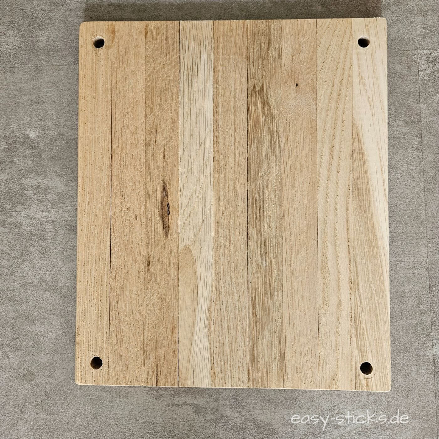 Bohrmarkierungen an den Ecken der Holzplatte für die spätere Montage