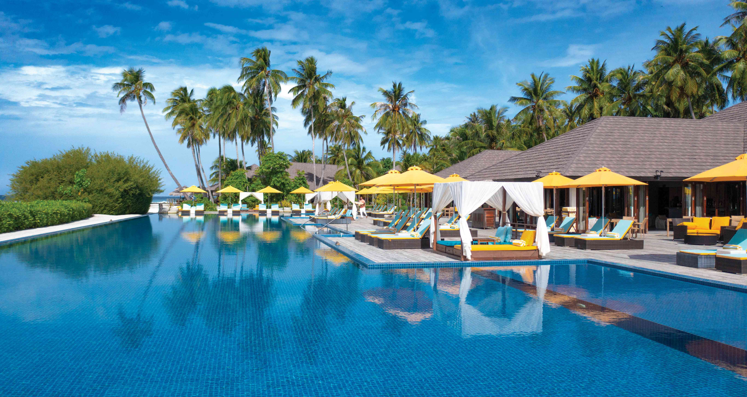 A view of The Liquid pool at Atmosphere Kanifushi, surrounded by sun loungers and cabanas for sunbathing. 