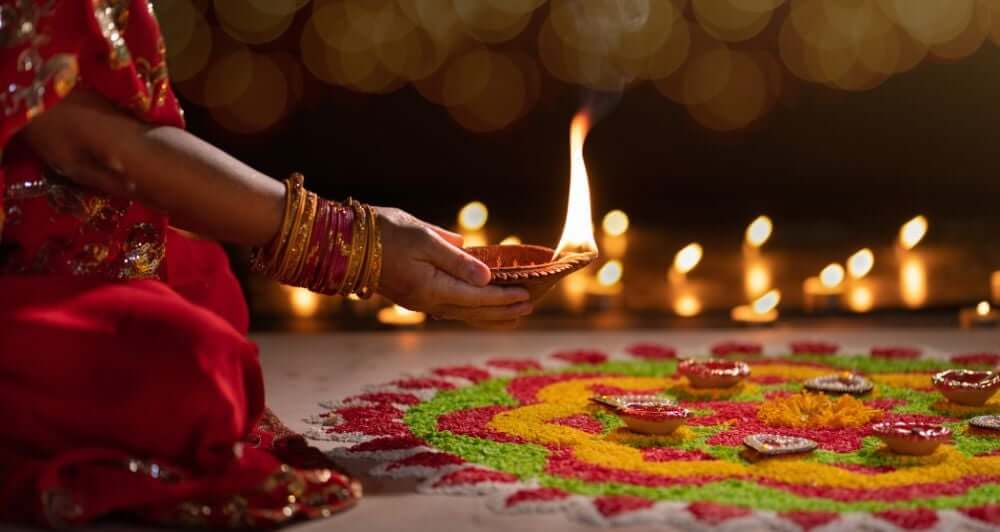 a women praying, and candels burning in the background, clourful salts decorated infront to place the blessed candle in the middle of.