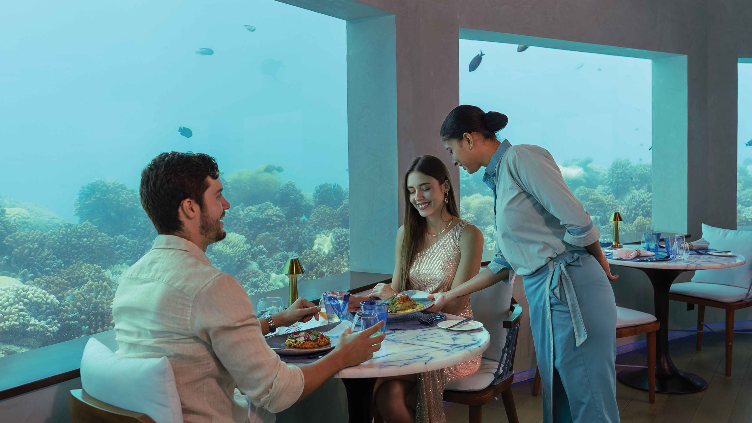 A couple at a Colours of OBLU property, OBLU SELECT Lobigili, dining in the underwater restaurant. 