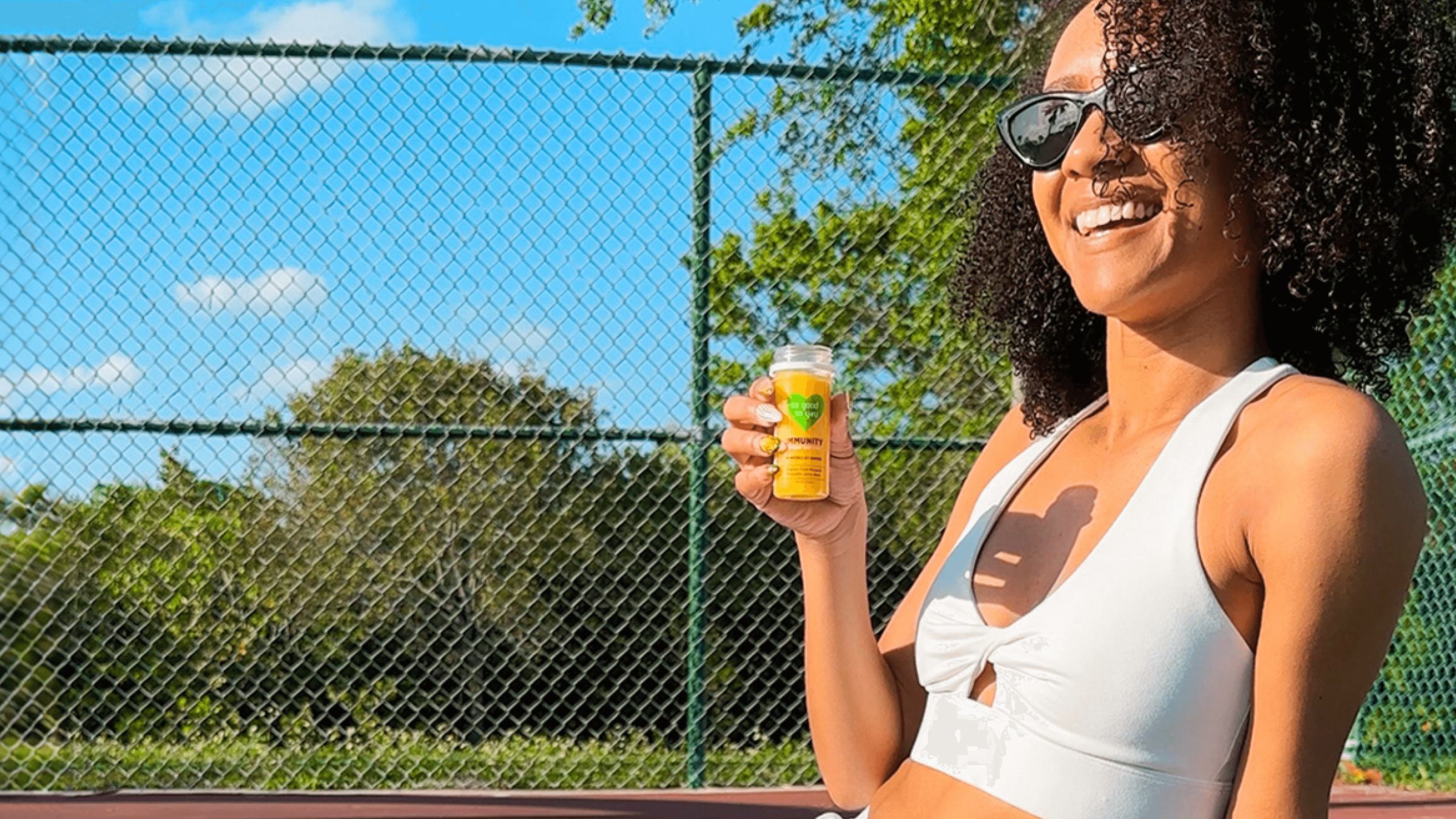 Girl drinking an Immunity Shot on the tennis court.