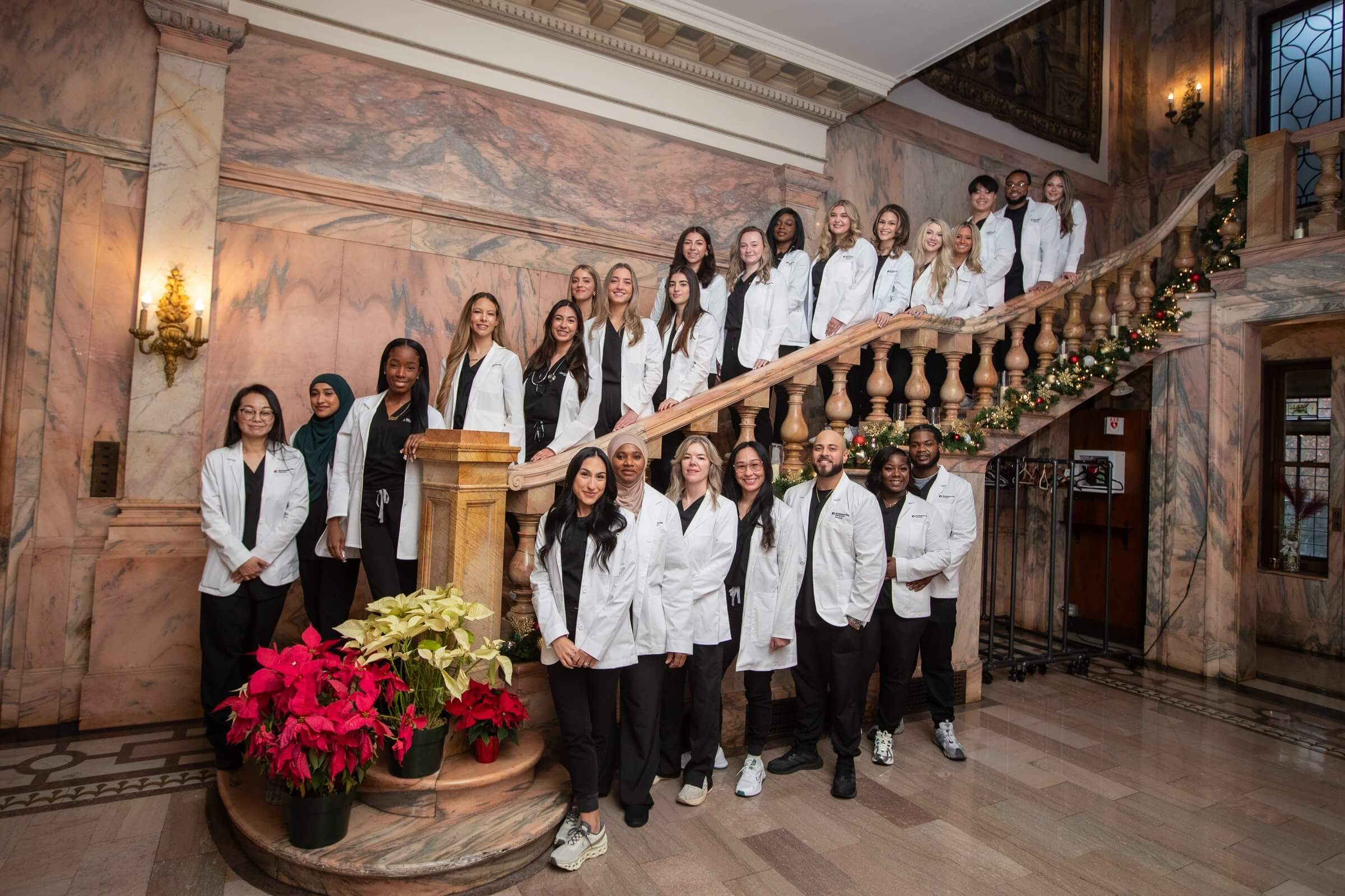 Nursing students in white coats standing on the grand staircase in Reid Castle