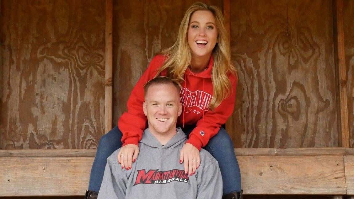 Two people sitting together inside a wooden dugout, with one person sitting slightly above the other in a casual pose.