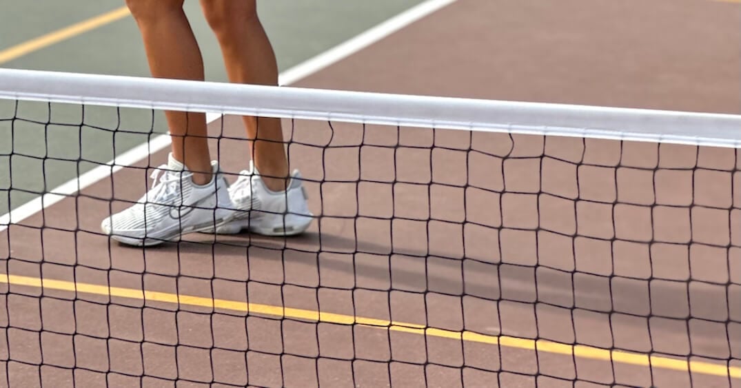 Close up image on a pickleball net and shoes on a court