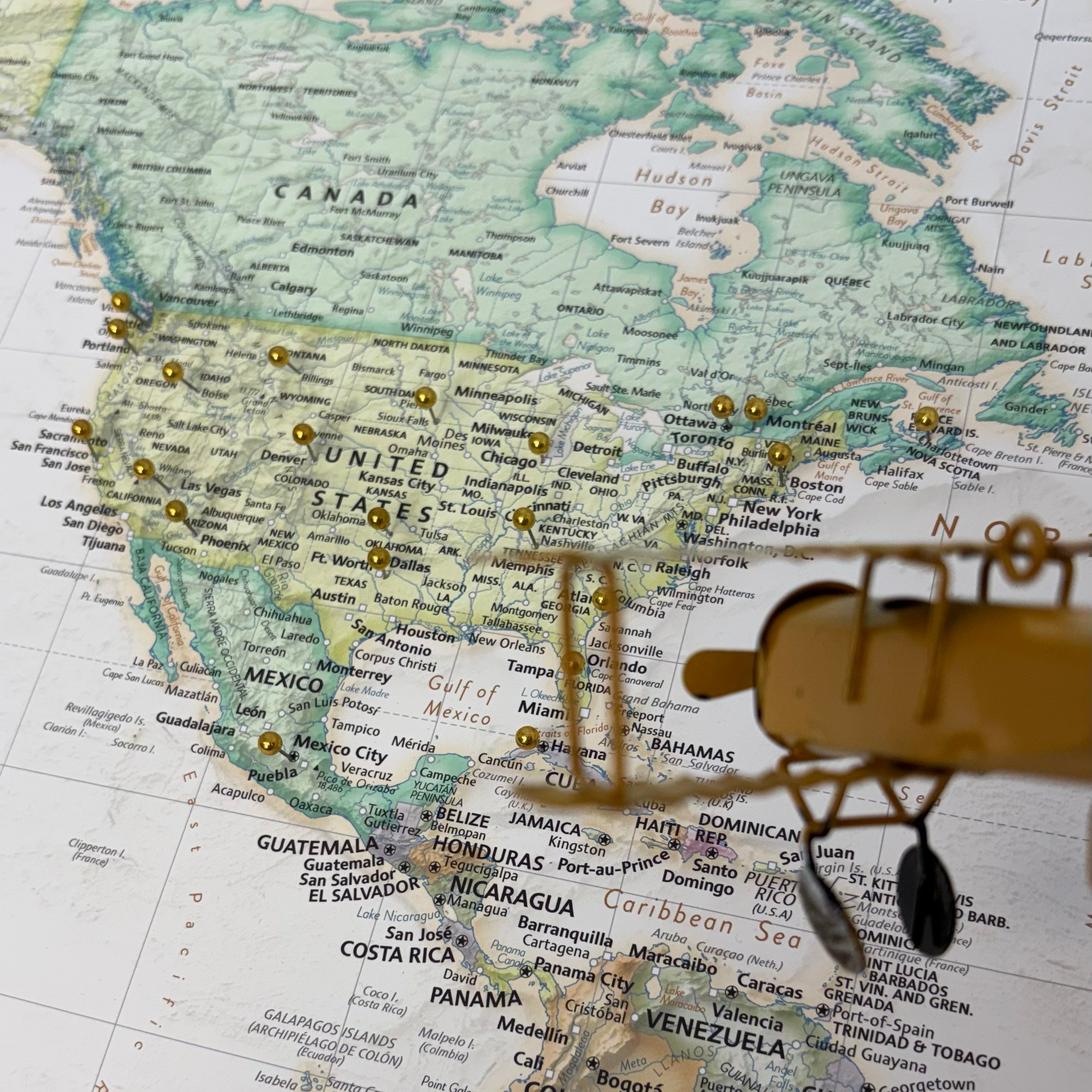 push pin travel map mocked up with pins and toy airplane coming in for a buzz