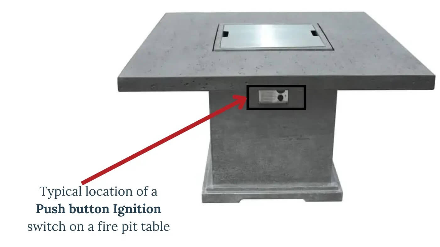 A concrete square fire pit table with a closed burner cover. A red arrow points to a rectangular push-button ignition switch located on the side of the table's base.