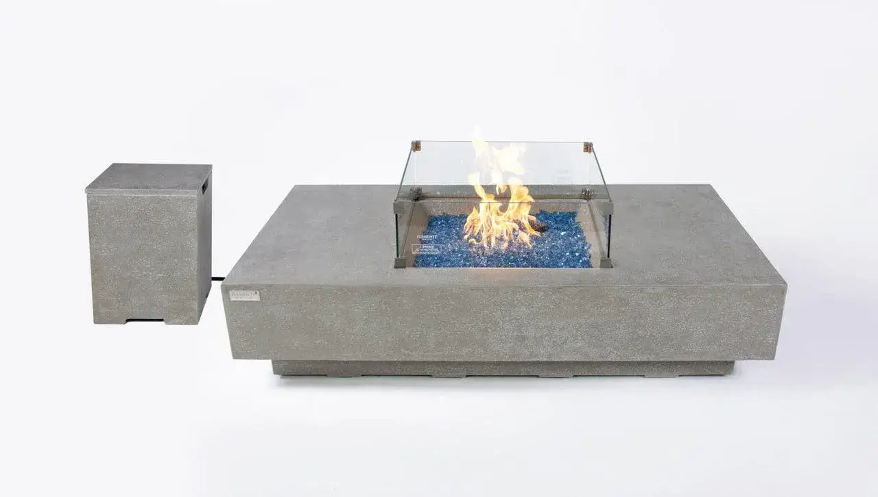 Light grey concrete square fire table with glass wind guard and separate tank cover on white background.