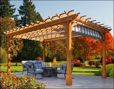 A cedar wooden structure with a retractable fabric roof, surrounded by a patio furniture set and colorful fall foliage.