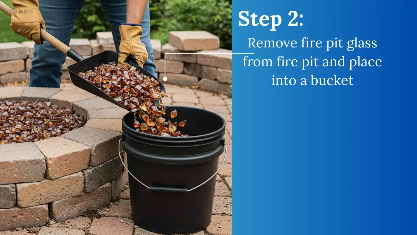 man using shovel to remove bronze fire pit glass from fire pit into a black plastic bucket