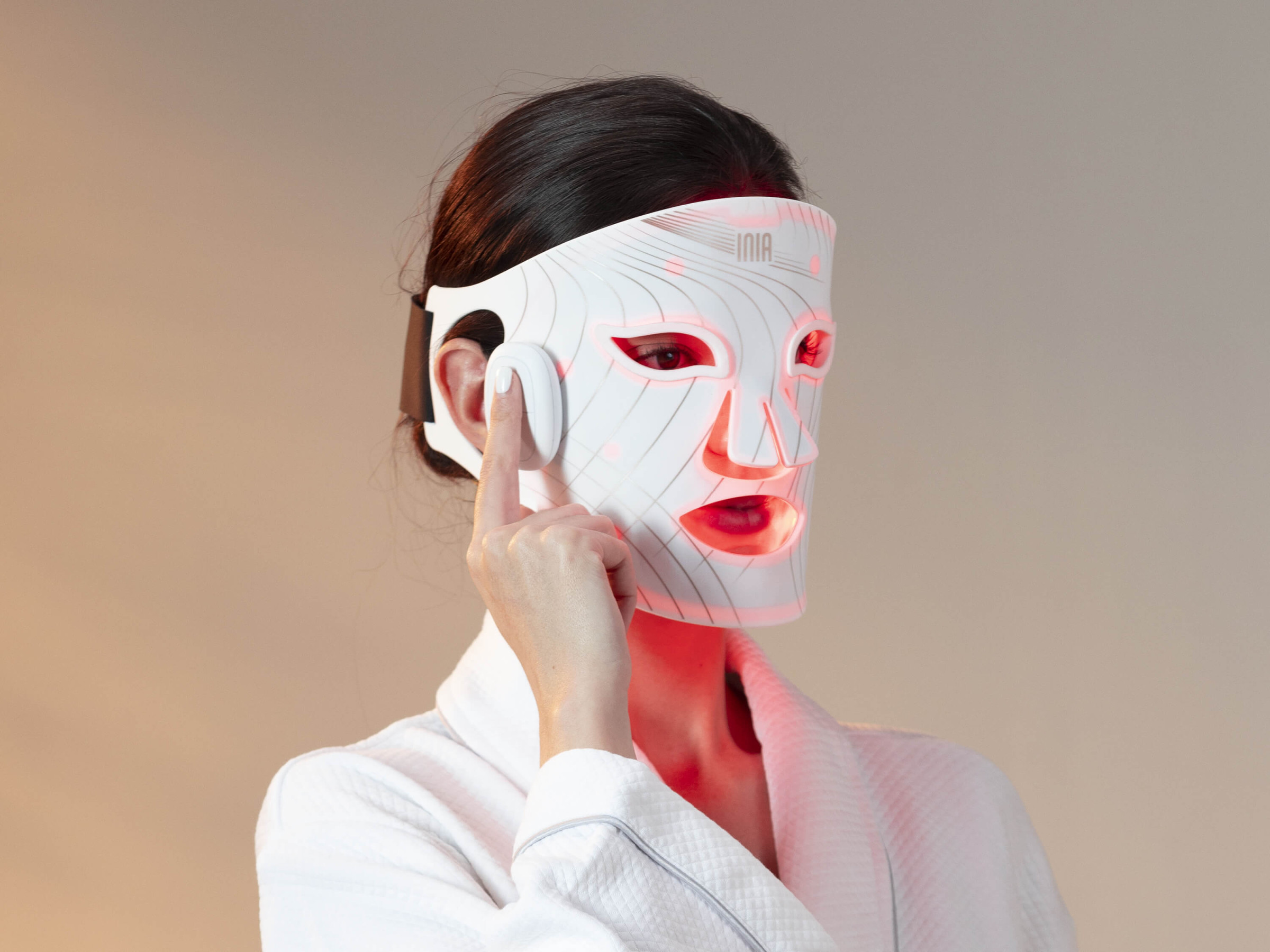 Woman using red light therapy mask at home