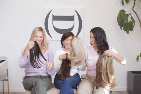 Three women holding different types of hair toppers to demonstrate the difference between Remy hair, Virgin hair, and 100% Human hair.