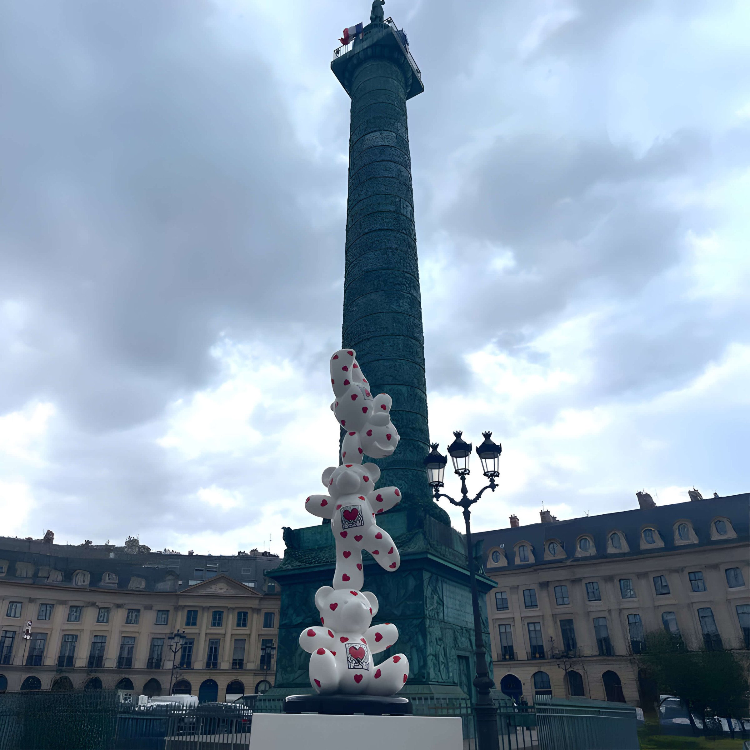 Stacked White Bear Sculpture – A tower of white bear sculptures with red hearts, displayed in a historic Parisian square.