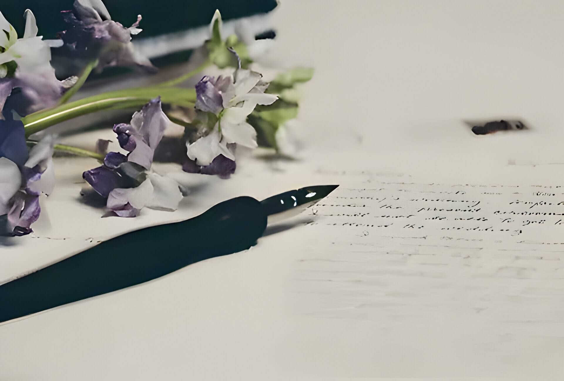 white paper, a black pen and purple flowers