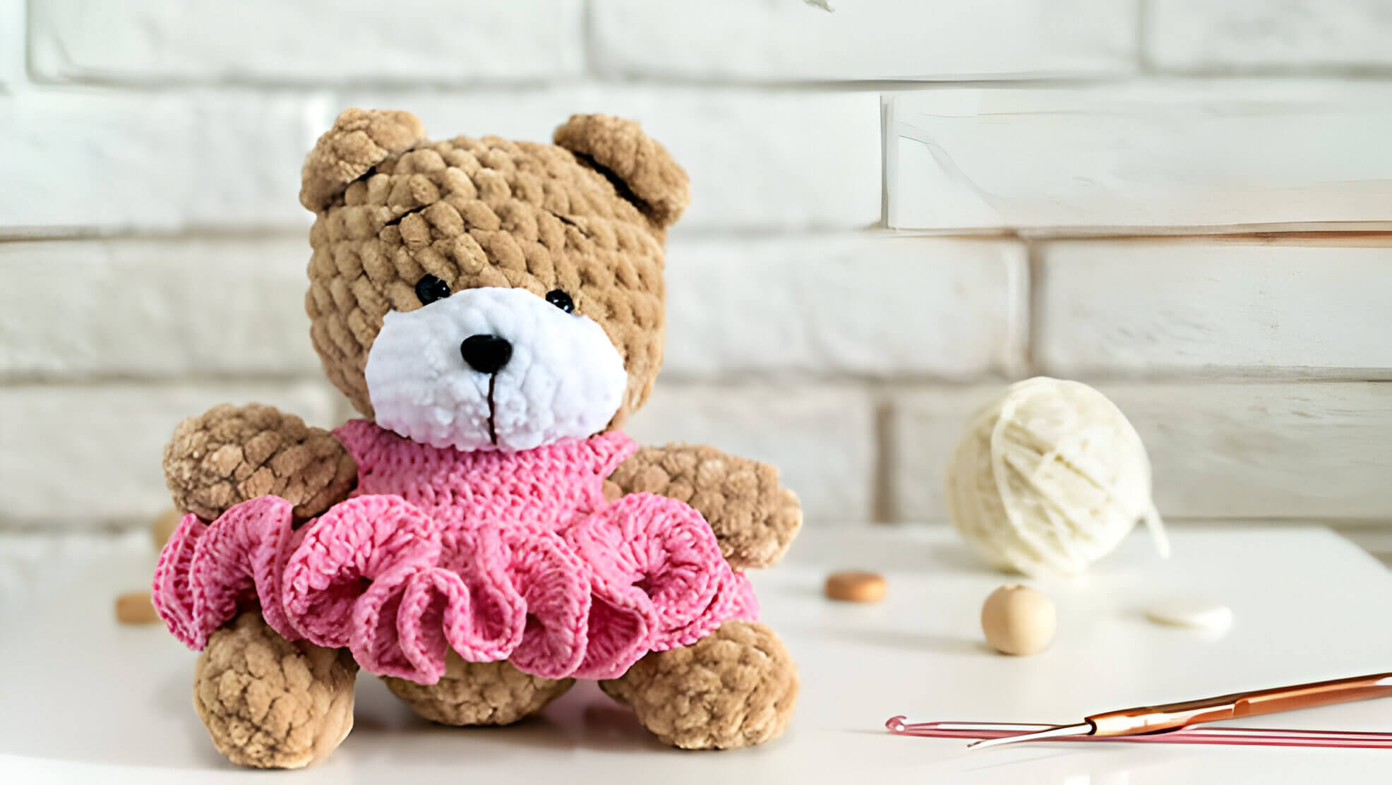 a brown crochet bear in a pink dress