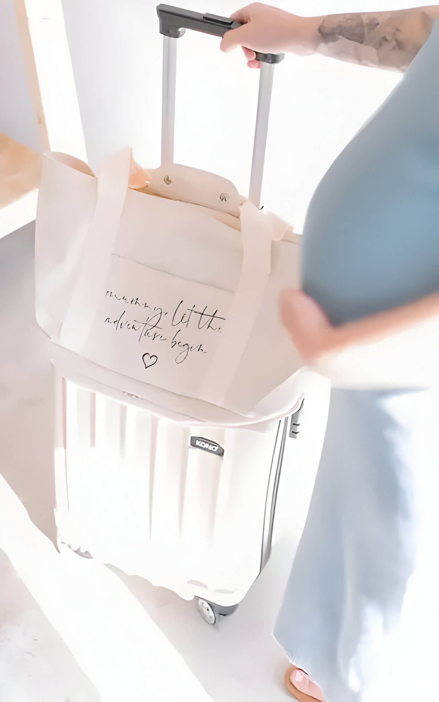 A white baby bag on top of a white suitcase, with a pregnant lady baby bump