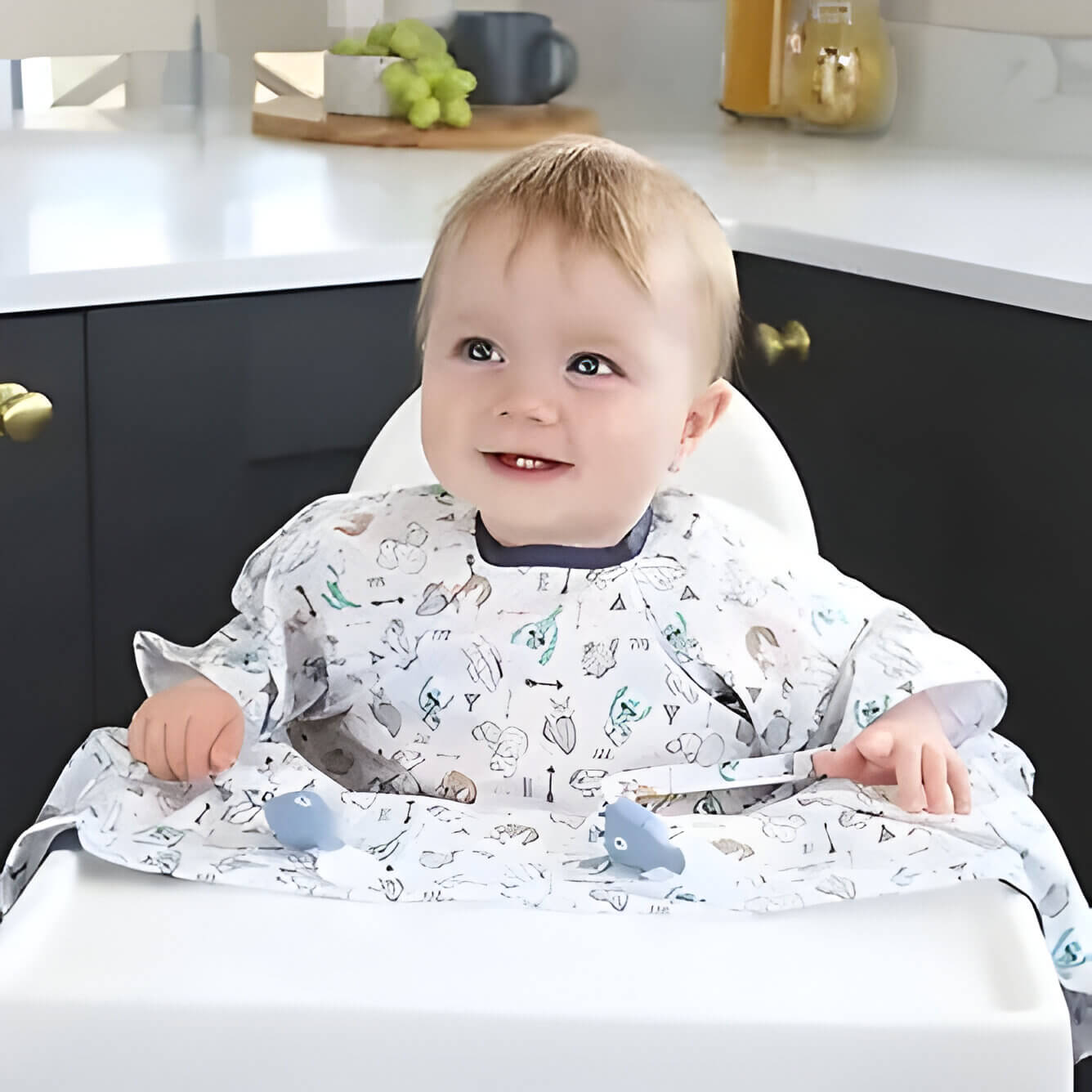 A baby wearing a full coverage bib sat in a highchair