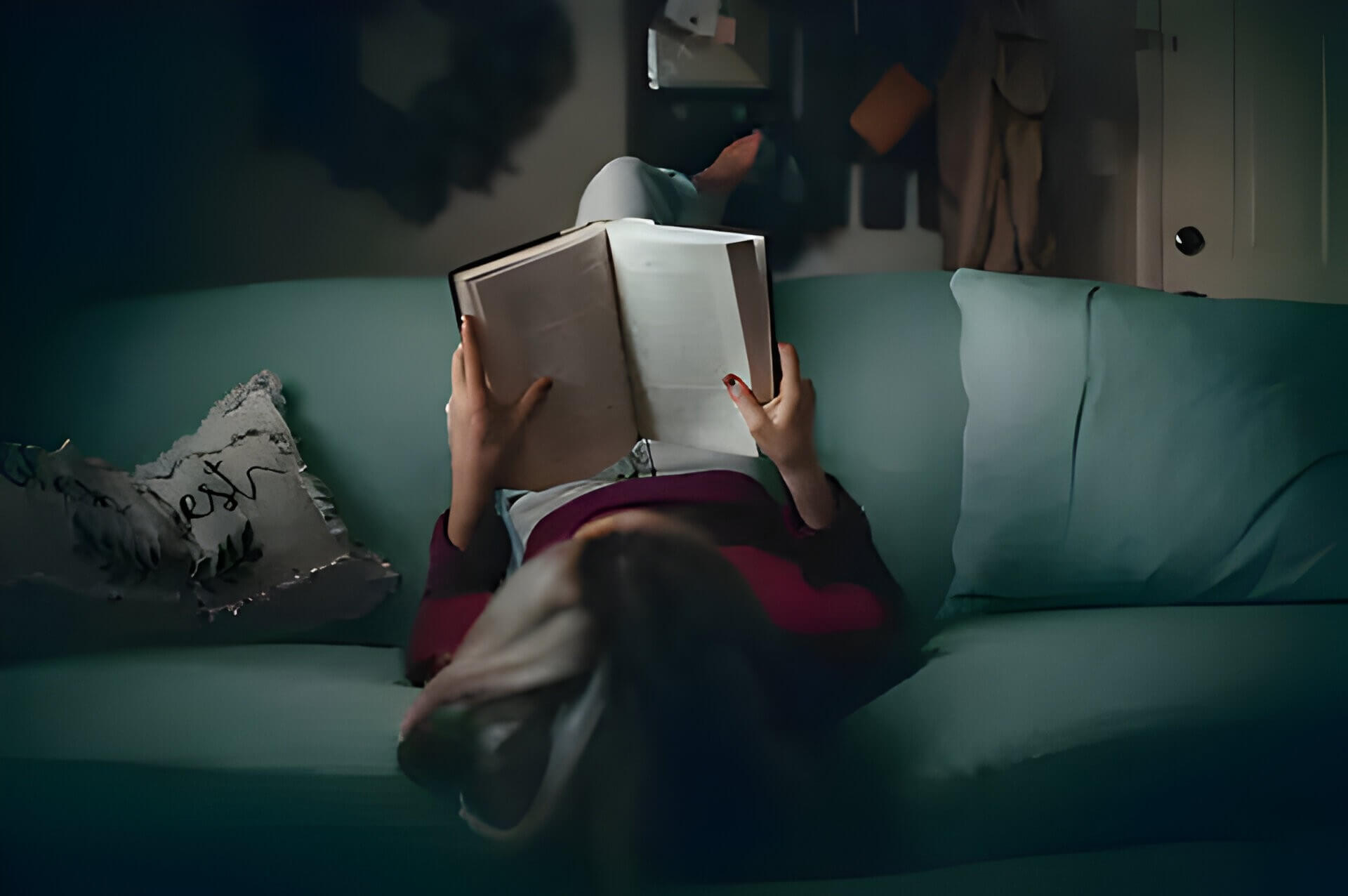 an Ariel view on a lady on a green sofa reading a book